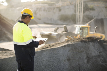 Worker standing at quarry, using clipboard - ZEF13733