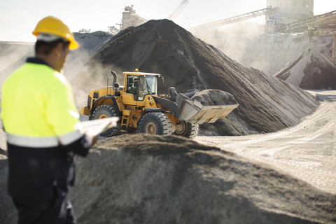 Worker standing at quarry, using clipboard stock photo