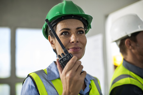 Female quarry worker standing in site office talking on radio device stock photo