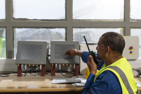 Arbeiter im Büro der Baustelle spricht in ein Funkgerät, lizenzfreies Stockfoto