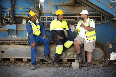 Arbeitskollegen im Steinbruch sitzen auf einer Maschine und machen eine Pause - ZEF13779