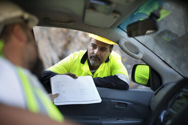 Worker handing over documents to colleague sitting in car - ZEF13787