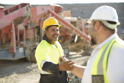 Two quarry workers shaking hands stock photo