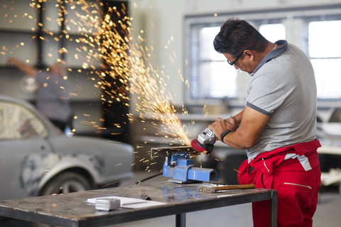 Mechaniker mit Winkelschleifer in einer Autowerkstatt, lizenzfreies Stockfoto