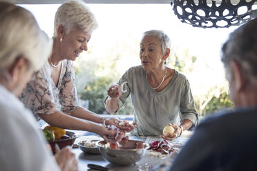 Ältere Frau bereitet mit Hilfe ihrer Freunde das Mittagessen auf der Terrasse vor - ZEF13839