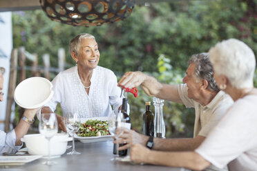 Smiling senior woman serving lunch on terrace - ZEF13840