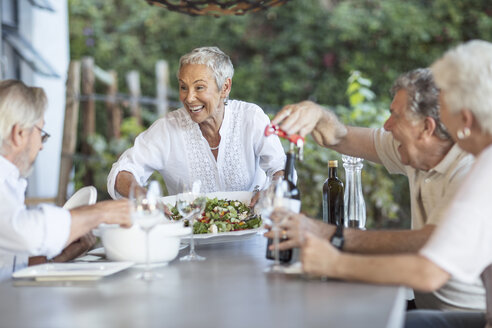 Lächelnde Seniorin serviert Mittagessen auf der Terrasse - ZEF13842