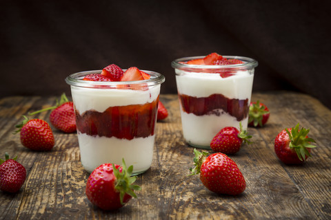 Two glasses of Greek yogurt with strawberries on wood stock photo