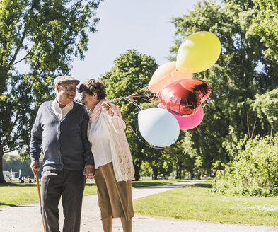 Glückliches älteres Paar mit Luftballons in einem Park - UUF10644