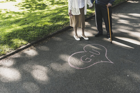 Senior couple drawed love heart with initials on tarmac - UUF10656