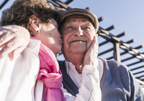 Porträt eines glücklichen älteren Mannes, der von seiner Frau geküsst wird - UUF10658