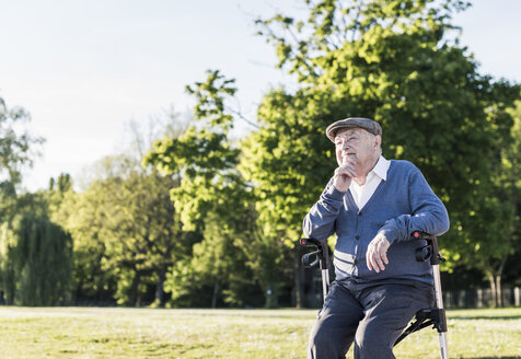 Nachdenklicher älterer Mann, der auf seinem Rollator in der Natur sitzt - UUF10669