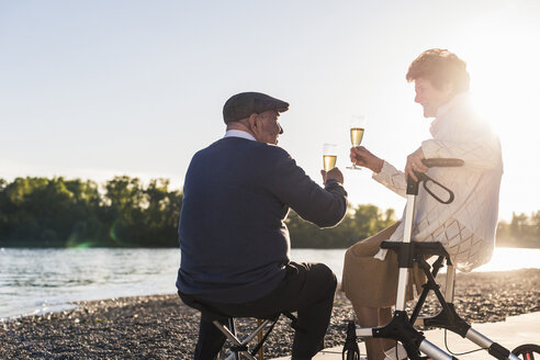 Seniorenpaar stößt bei Sonnenuntergang mit Sekt an - UUF10671