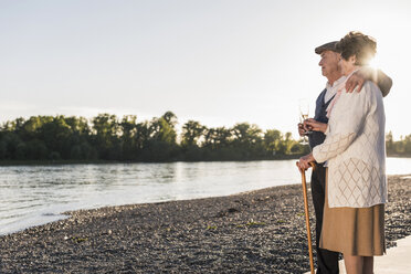 Älteres Paar am Strand mit Champagnergläsern bei Sonnenuntergang - UUF10674