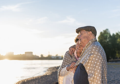 Älteres Paar entspannt sich bei Sonnenuntergang am Strand - UUF10688