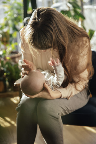 Mutter streichelt ihr neugeborenes Baby zu Hause, lizenzfreies Stockfoto