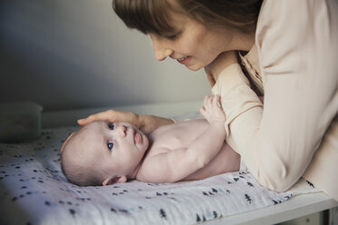 Mother caressing her naked newborn baby boy on changing table - MFF03574