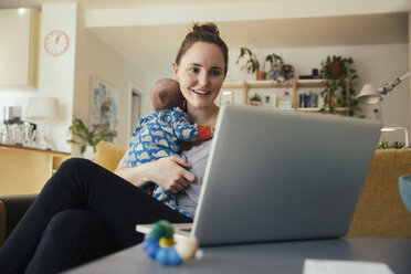 Mutter benutzt Laptop und hält ihr neugeborenes Baby zu Hause - MFF03581