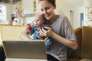 Mother and newborn baby taking a video call at home - MFF03587