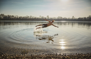 Germany, Bavaria, Feldkirchen, man jumping in lake - KDF00736