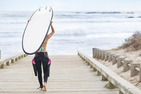 Frau geht mit Surfbrett zum Strand, lizenzfreies Stockfoto