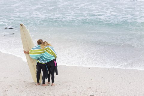 Pärchen am Strand mit Surfbrett, lizenzfreies Stockfoto