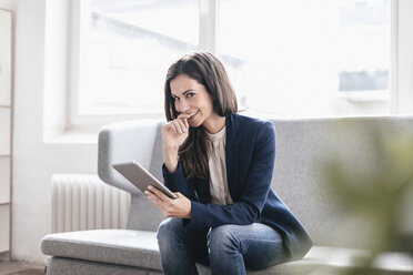 Portrait of smiling businesswoman with tablet on couch - JOSF00957
