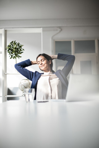 Businesswoman at table leaning back stock photo