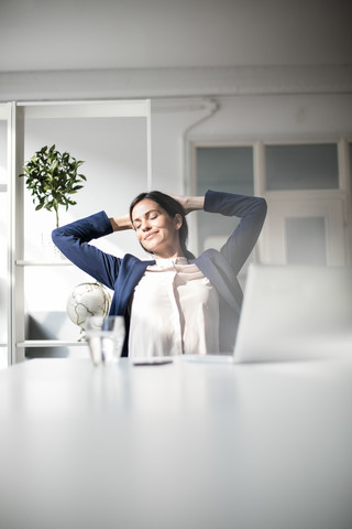 Geschäftsfrau am Tisch lehnt sich zurück, lizenzfreies Stockfoto