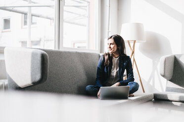 Smiling businesswoman using laptop on couch - JOSF00965