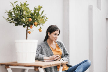 Woman relaxing next to orange tree - JOSF00980