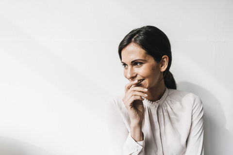 Glückliche Frau vor einer weißen Wand, lizenzfreies Stockfoto