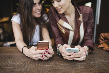 Two young women using cell phones in a bar - MRAF00201