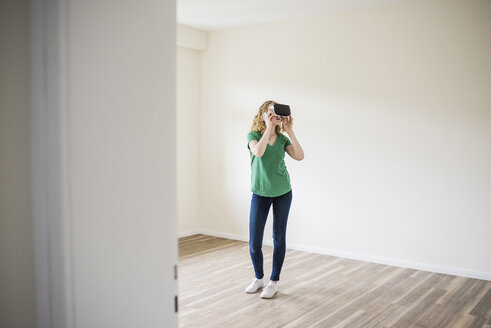 Frau in leerer Wohnung mit VR-Brille - UUF10694