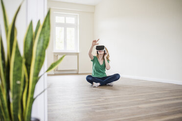 Woman in empty apartment wearing VR glasses - UUF10696