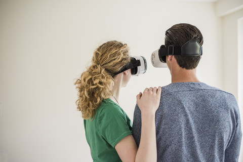 Junges Paar in leerer Wohnung mit VR-Brille, lizenzfreies Stockfoto