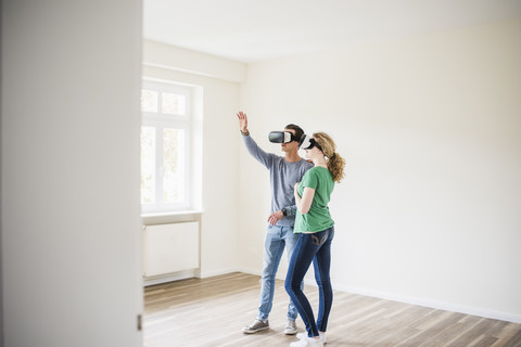 Young couple in empty apartment wearing VR glasses stock photo