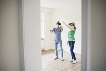 Young couple discussing in empty apartment wearing VR glasses - UUF10709