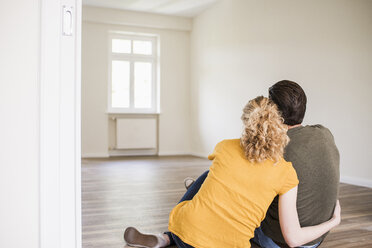 Junges Paar in neuer Wohnung auf dem Boden sitzend - UUF10712