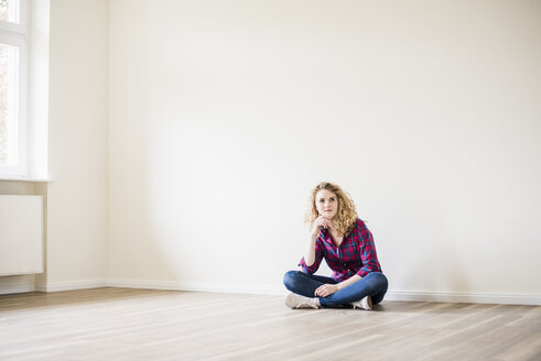 Junge Frau in neuer Wohnung auf dem Boden sitzend - UUF10714