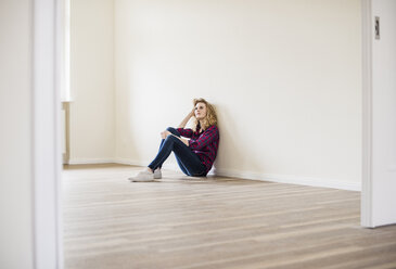 Young woman in new home sitting on floor - UUF10715