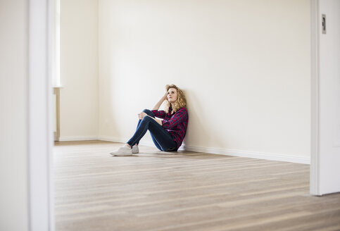Junge Frau in neuer Wohnung auf dem Boden sitzend - UUF10715