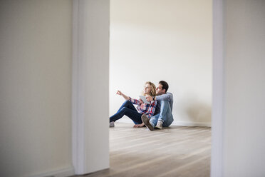 Junges Paar in neuer Wohnung sitzt mit Tablet auf dem Boden - UUF10722