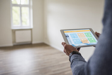 Mann in neuer Wohnung nutzt Tablet mit Smart-Home-Anwendungen - UUF10725