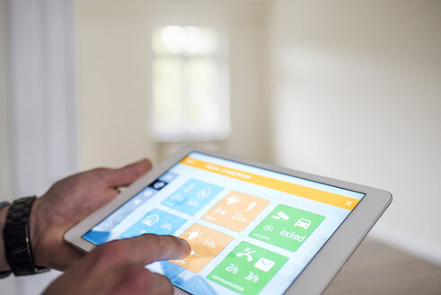 Mann in neuer Wohnung nutzt Tablet mit Smart-Home-Anwendungen - UUF10726