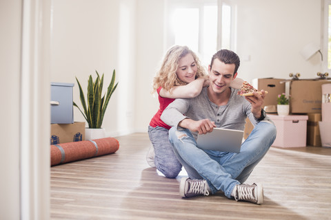 Junges Paar in neuer Wohnung sitzt mit Tablet auf dem Boden, lizenzfreies Stockfoto