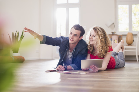 Young couple in new home lying on floor with tablet choosing from color sample stock photo