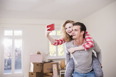 Happy young couple in new home taking a selfie - UUF10749