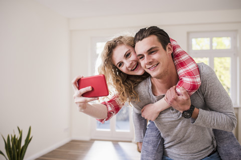 Glückliches junges Paar im neuen Haus, das ein Selfie macht, lizenzfreies Stockfoto