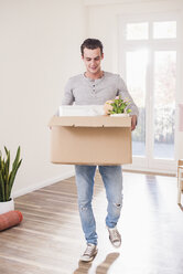 Young man carrying cardboard box in new home - UUF10755